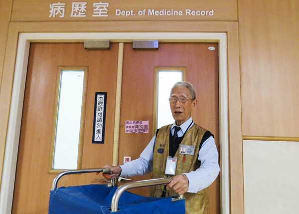 封師兄推著病歷運送車在病歷室門口的獨照。(曾秀英攝)