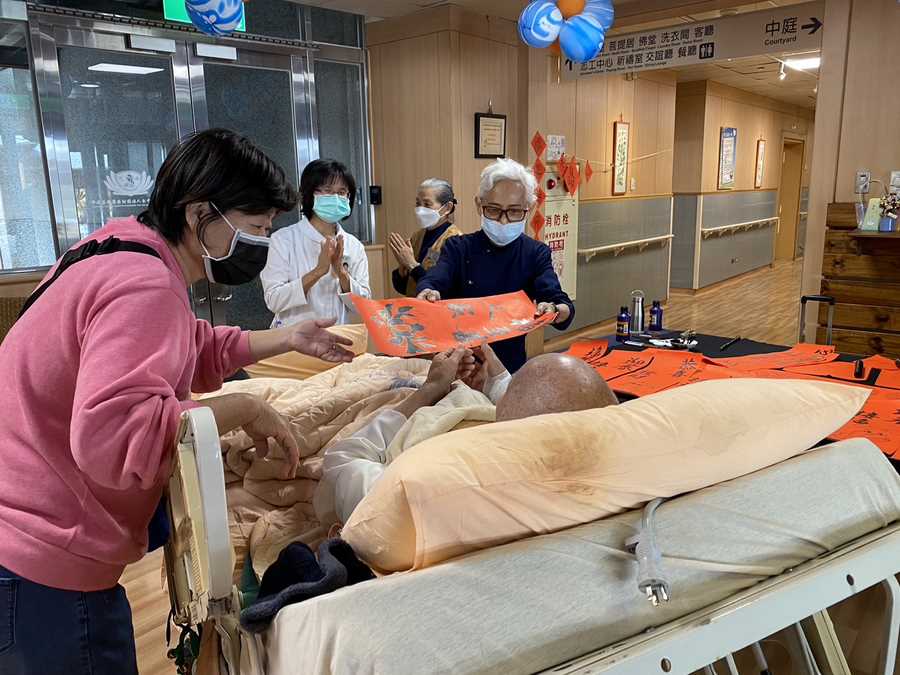 慈濟志工林富卿（右一）現場揮毫寫春聯送給病人。（吳宛育攝）