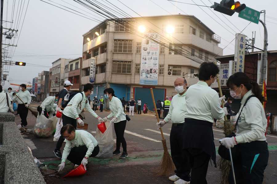 臺中慈濟醫院院長簡守信（左下）蹲在路邊以畚箕加木板清理街道垃圾。
