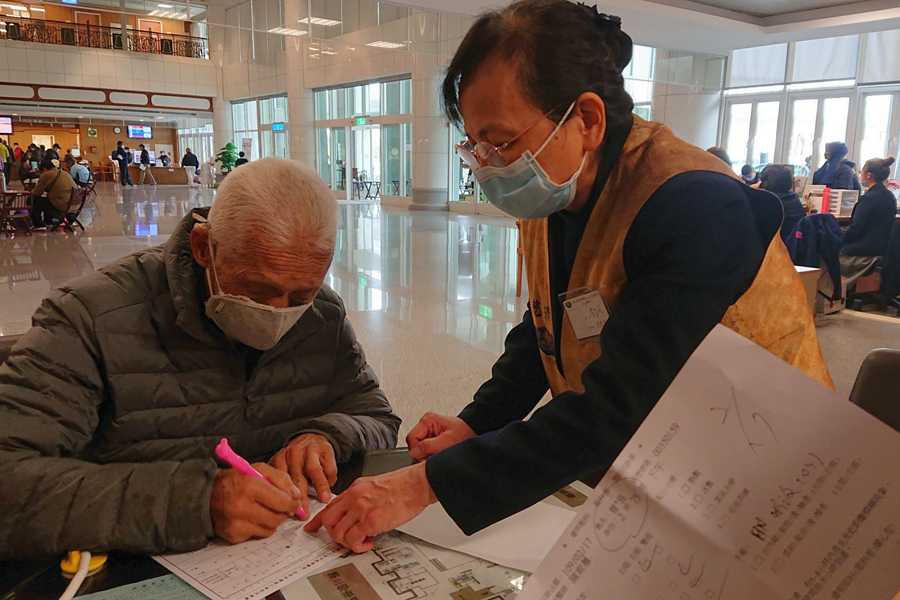 李芷鳳親切地為初診會眾，解說如何填寫初診單。
