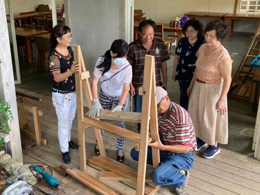 長輩們認真學習以廢木料木工創作書架與書桌。（陳又華攝）